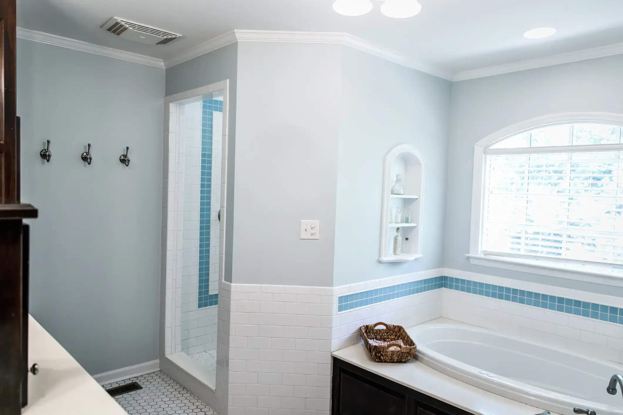 A bathroom in soft blue gray with white tile, a glass shower and a soaking tub