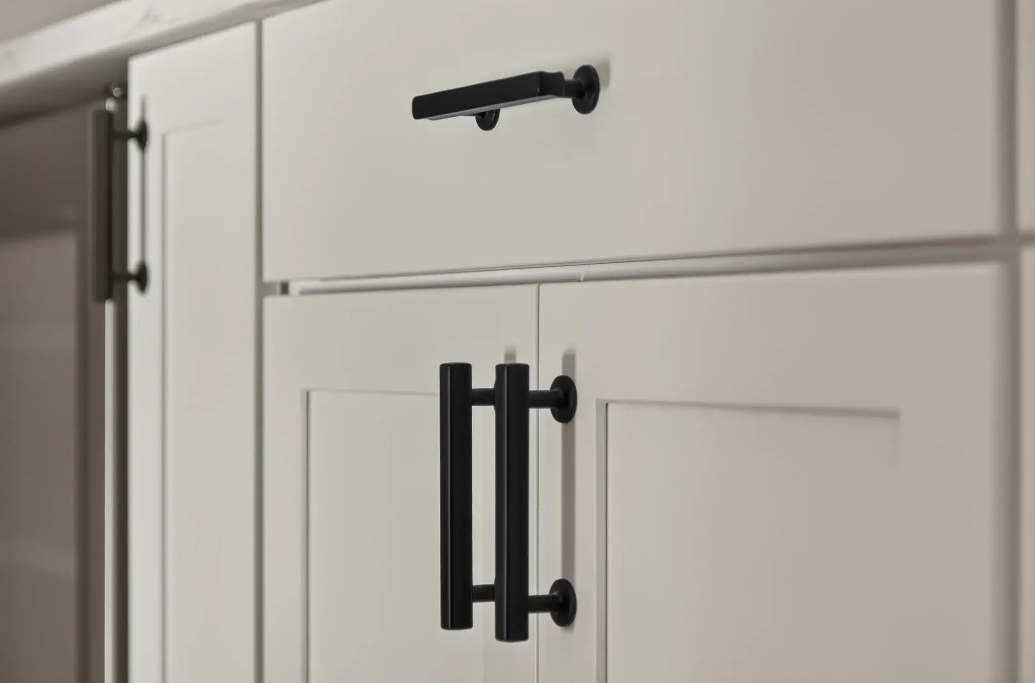Close up of white painted cabinets with black hardware