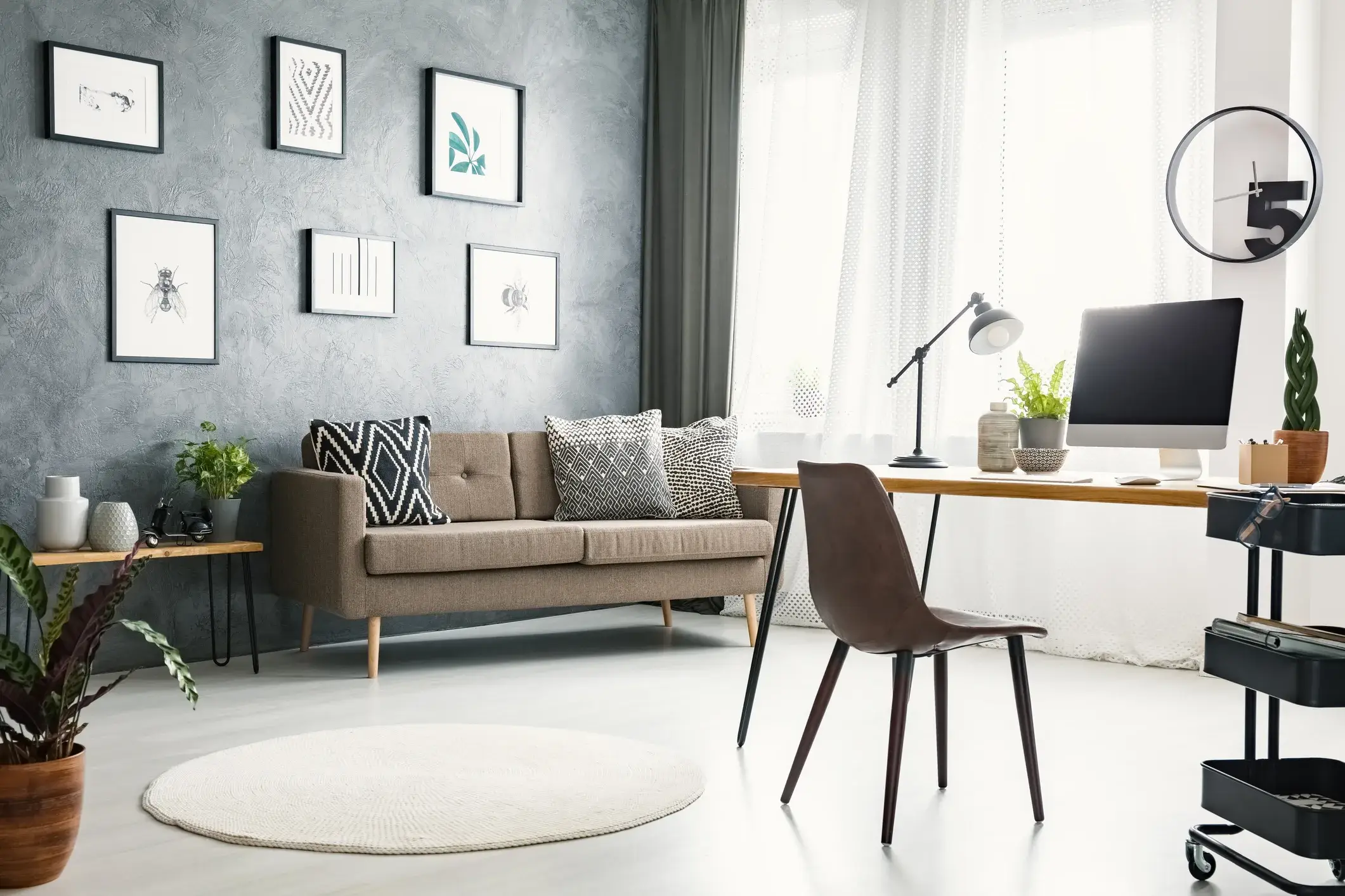 A bright home office with gray painted walls, a desk and a sofa