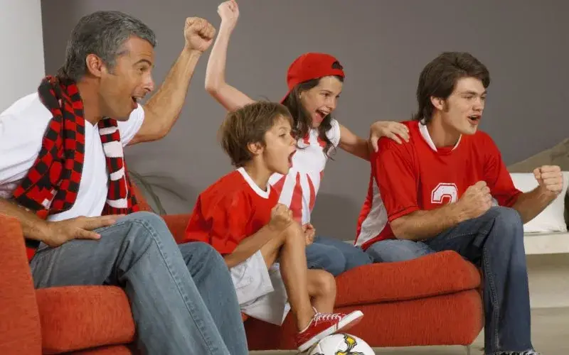 Family watching a game in a living room painted red and black - Interior Painters