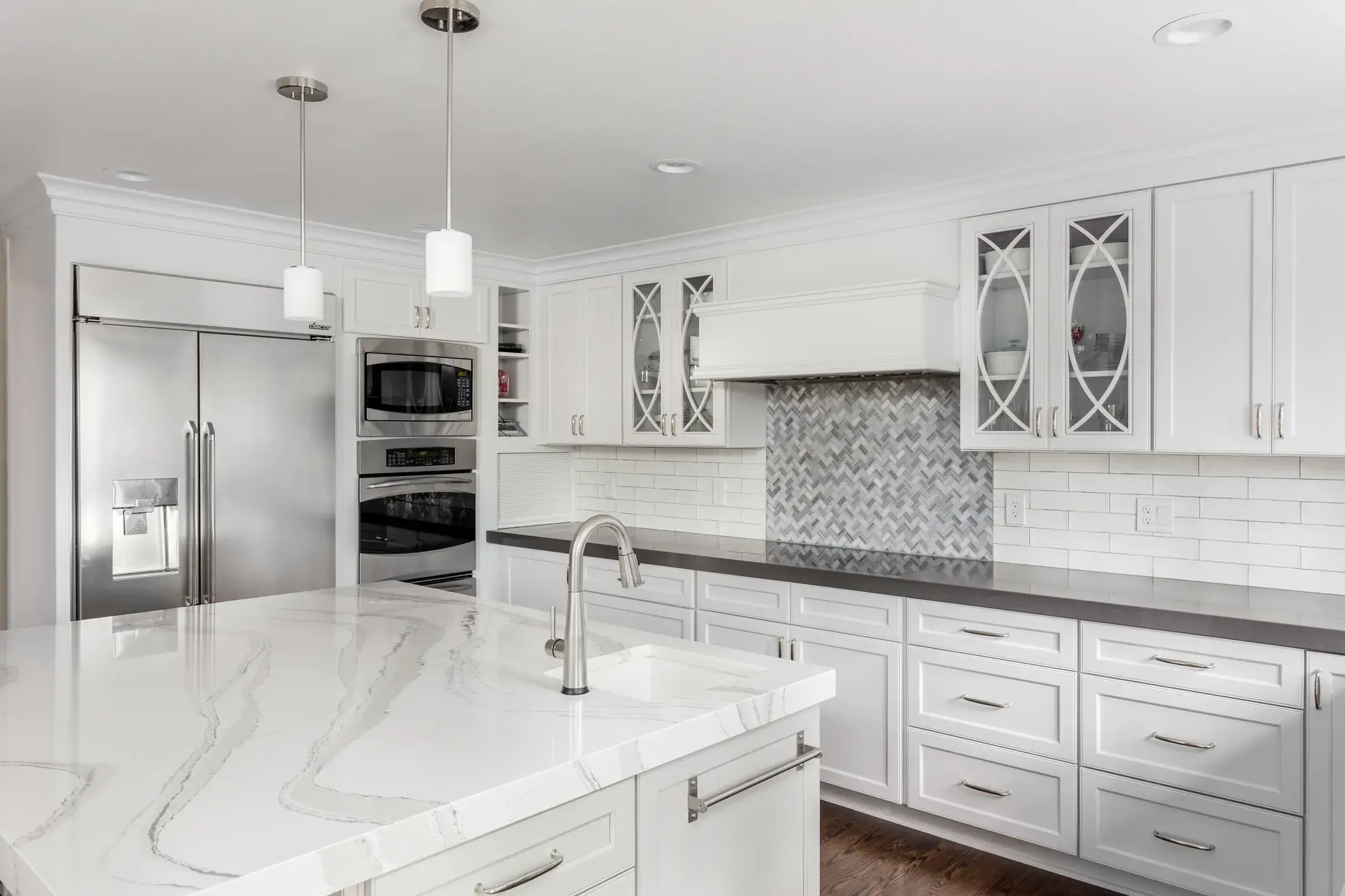 White kitchen cabinets with a gray backsplash and black countertops