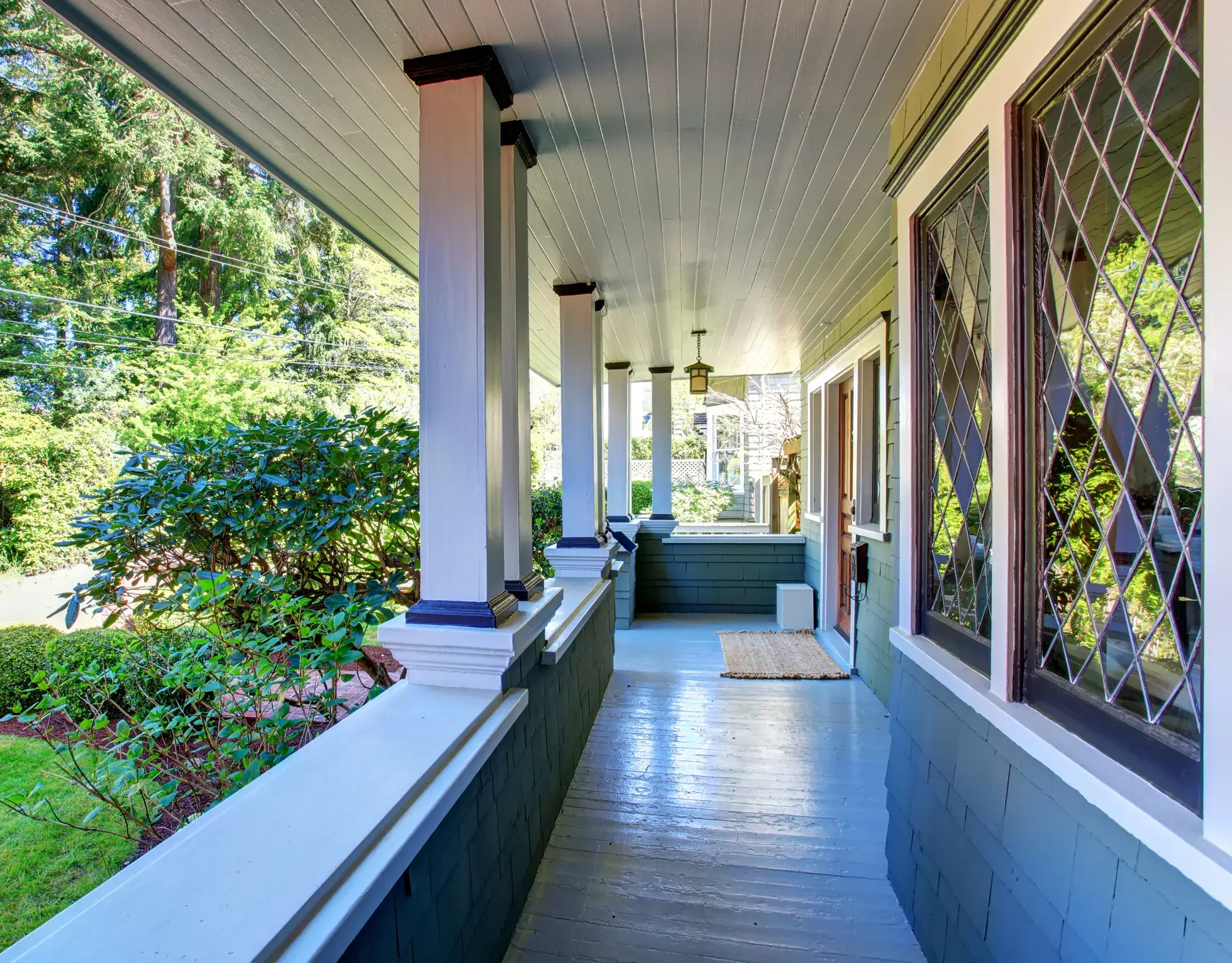 A covered front porch with a pale blue painted ceiling and white columns